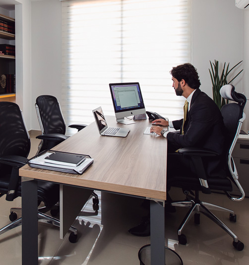 Homem em um escritório, trabalhando em um IMac e um MacBook